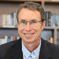 Dr. Andrew Newberg, expert on sexuality and spirituality, in front of a bookshelf featuring his book 'Sex, God, and the Brain.